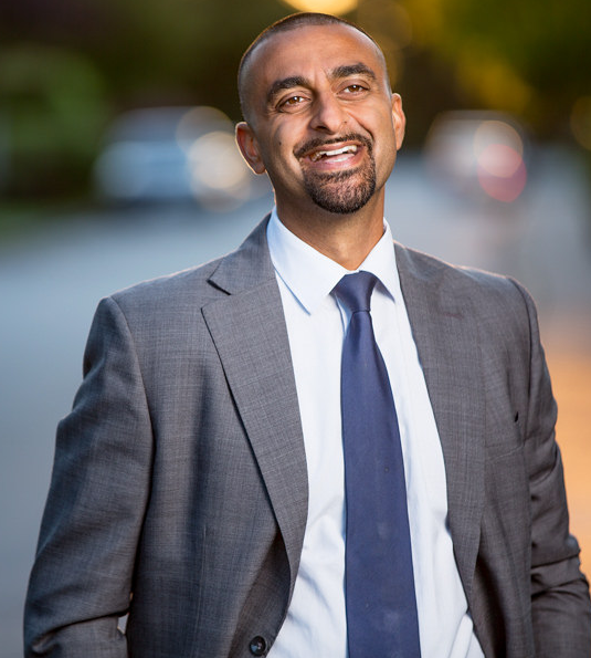 Headshot of Ravi Kahlon. He is wearing a full suit and seems to be standing outside.