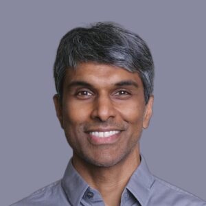 Headshot of Dr. Omar Khan, with a grey-purple background and matching shirt.